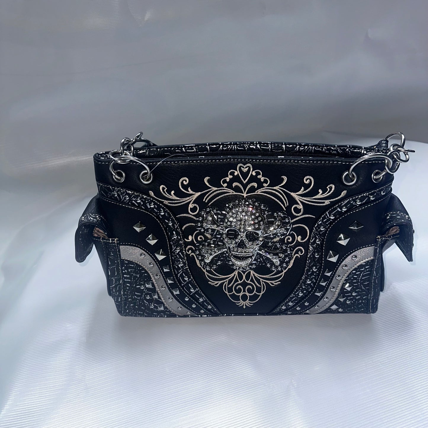 Black handbag with skull design and decorative elements on a white background
