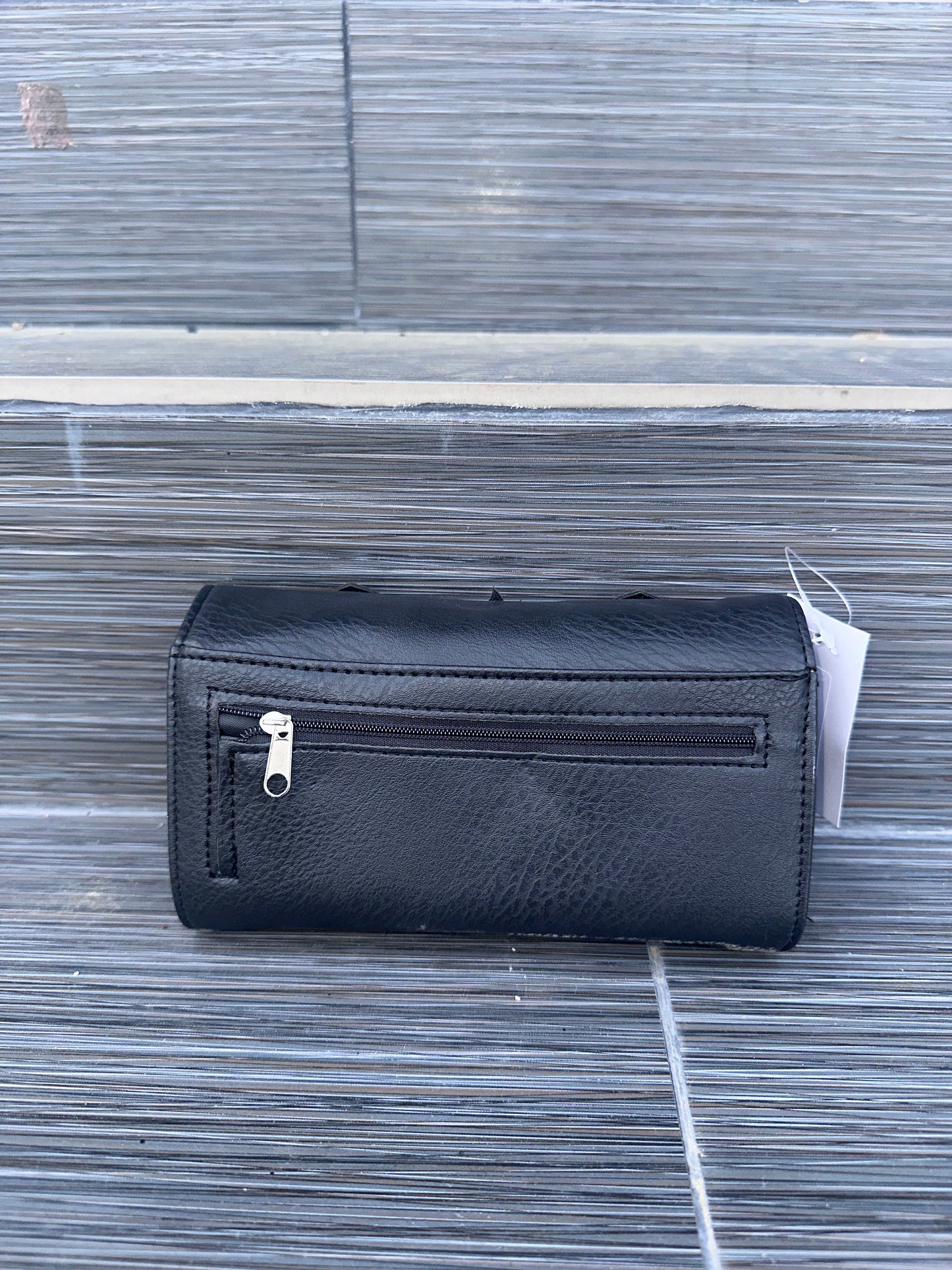 Black wallet with a tag on a textured surface