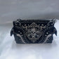 Black handbag with skull design and decorative elements on a white background