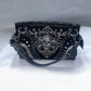 Black handbag with silver embellishments on a white background