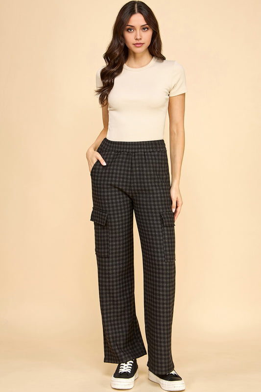 Woman wearing a beige top and checkered pants on a beige background