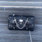 Black leather wallet with skull design and chain on a wooden surface