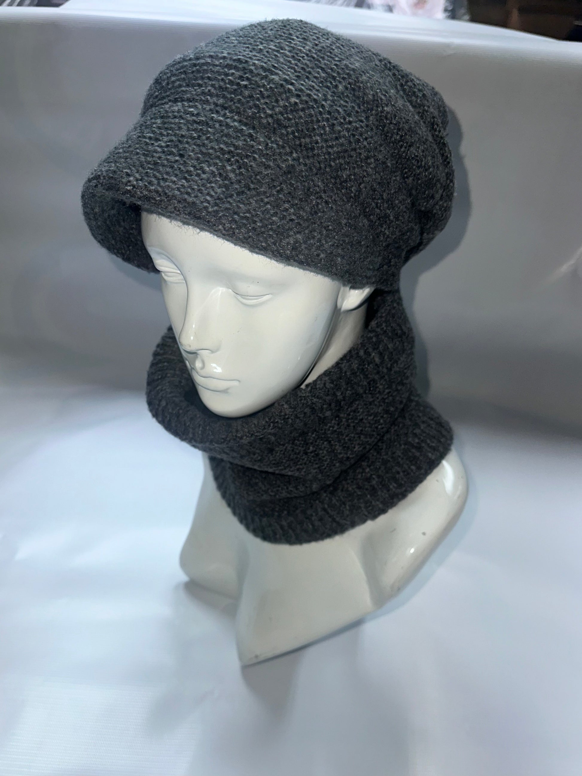 Mannequin head wearing a gray knit hat and scarf on a white background