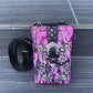 Pink camouflage phone case with black accents and a strap on a gray surface