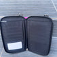 Black zippered pouch with multiple compartments on a textured surface