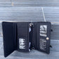 Open black wallet with multiple compartments on a wooden surface