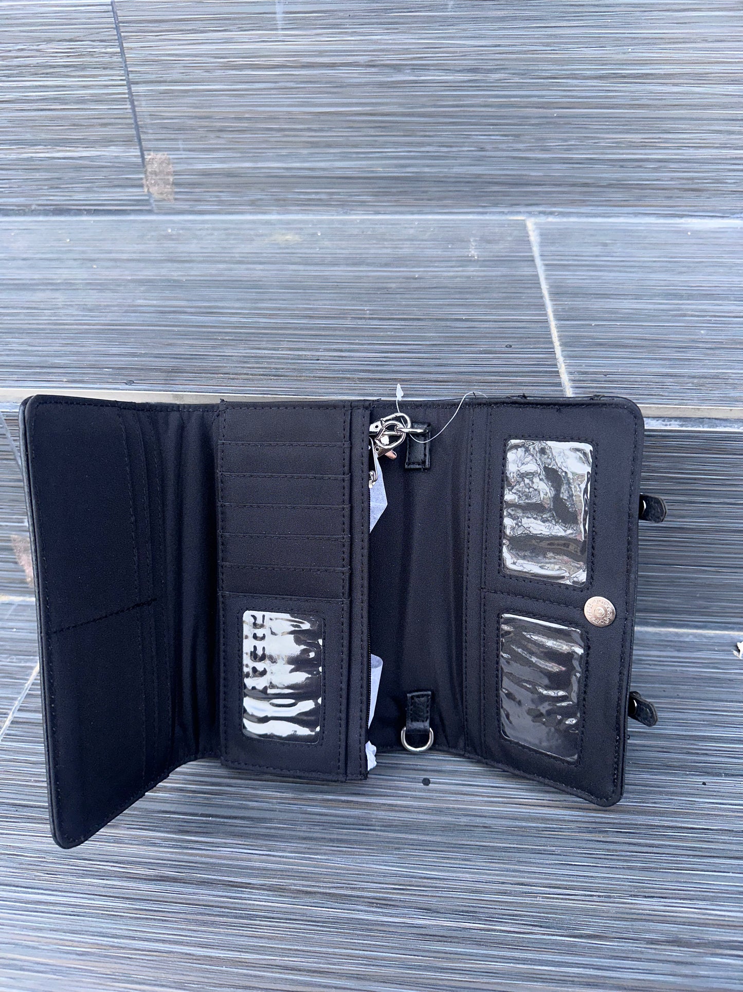 Open black wallet with multiple compartments on a wooden surface